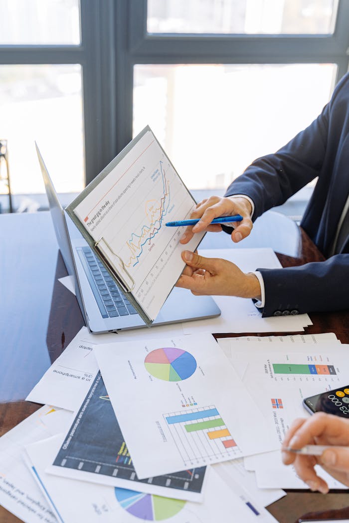 about-me-01 Business professionals discussing financial graphs and charts in an office setting.