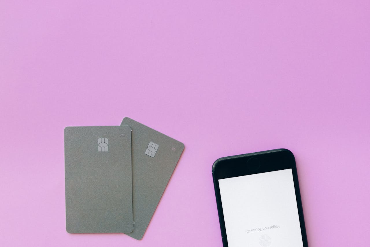 hero-img Flat lay of credit cards and smartphone on pink surface, symbolizing digital payment solutions.